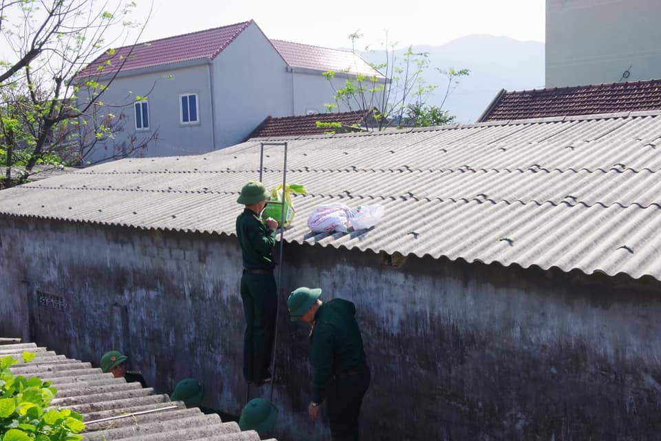 Bộ đội tấp cát vào bao bì, gia cố mái nhà giúp dân.