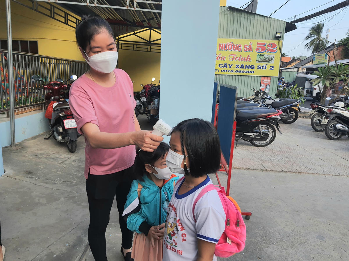 Các giáo viên trường mầm non Sơn Ca, TP Bạc Liêu đón và đo thân nhiệt, hướng dẫn rửa tay sát khuẩn cho các bé.