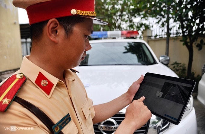 Cán bộ thuộc Cục CSGT sử dụng máy tính bảng xử lý vi phạm. Ảnh: Bá Đô.