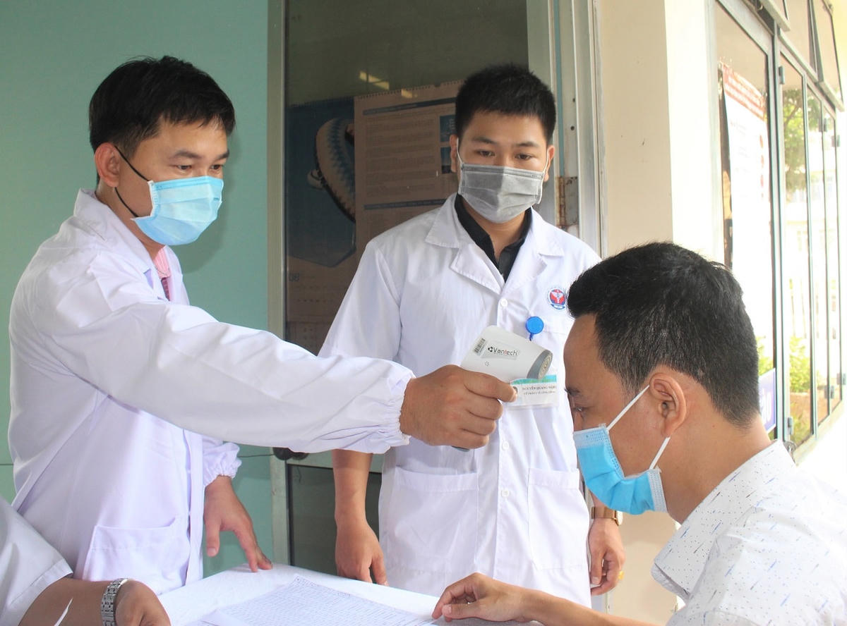 Kiểm tra thân nhiệt trước khi tiêm vaccine Covid-19. 