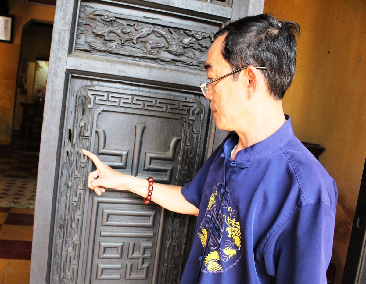 Nhân viên Chùa Ông ở TP Hội An chỉ cánh cửa gỗ bị mối mọt đục khoét.