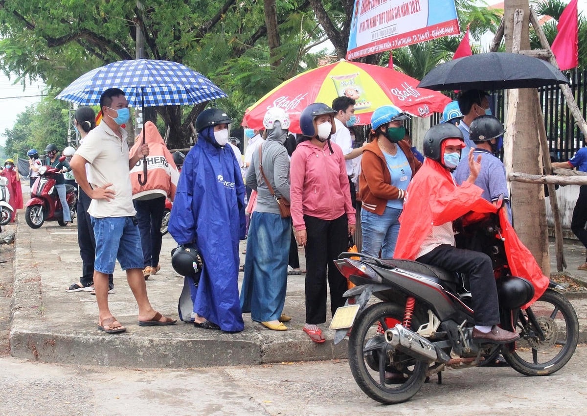 Phụ huynh đội mưa đứng ngoài cổng đợi con.
