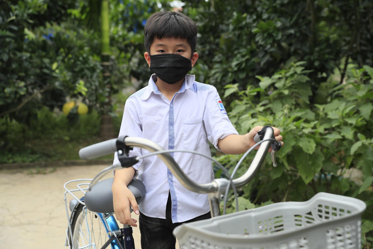 Bé Ngô Hồ Tiểu Phong bên chiếc xe đạp mới.