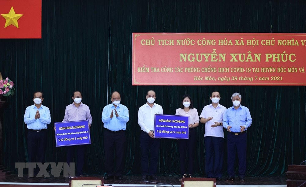 Chủ tịch nước Nguyễn Xuân Phúc và Chủ tịch UBTƯ MTTQ Việt Nam Đỗ Văn Chiến chứng kiến các doanh nghiệp trao hỗ trợ công tác phòng, chống dịch Covid-19 cho huyện Hóc Môn và huyện Củ Chi. Ảnh: Thống Nhất/TTXVN.