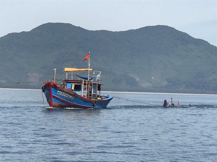 Lực lượng chức năng đang trục vớt ghe câu mực. Ảnh: N.Bình.