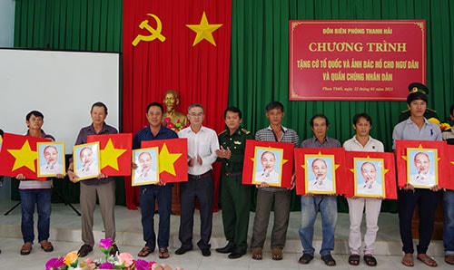 Thượng tá Trần Việt Hưng, Phó Chính ủy BĐBP tỉnh Bình Thuận và ông Lê Văn Chơn, Phó Chủ tịch UBND TP Phan Thiết tặng cờ Tổ quốc và ảnh Bác Hồ cho ngư dân.