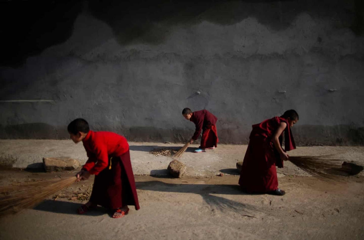 Những nhà sư trẻ quét dọn vỉa hè dọc con đường bên ngoài tu viện Phật giáo ở Godavari. Ảnh: Skanda Gautam / Zuma / Rex / Shutterstock.