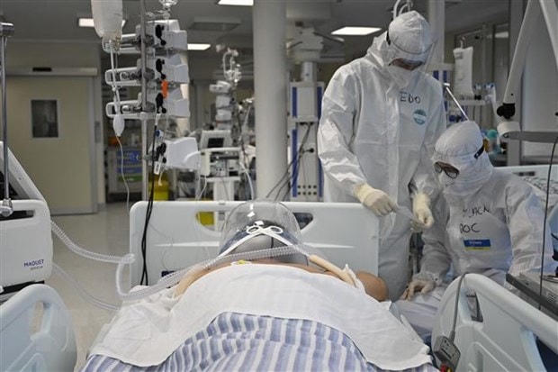 Nhân viên y tế điều trị cho bệnh nhân COVID-19 tại bệnh viện. (Ảnh: AFP/TTXVN)