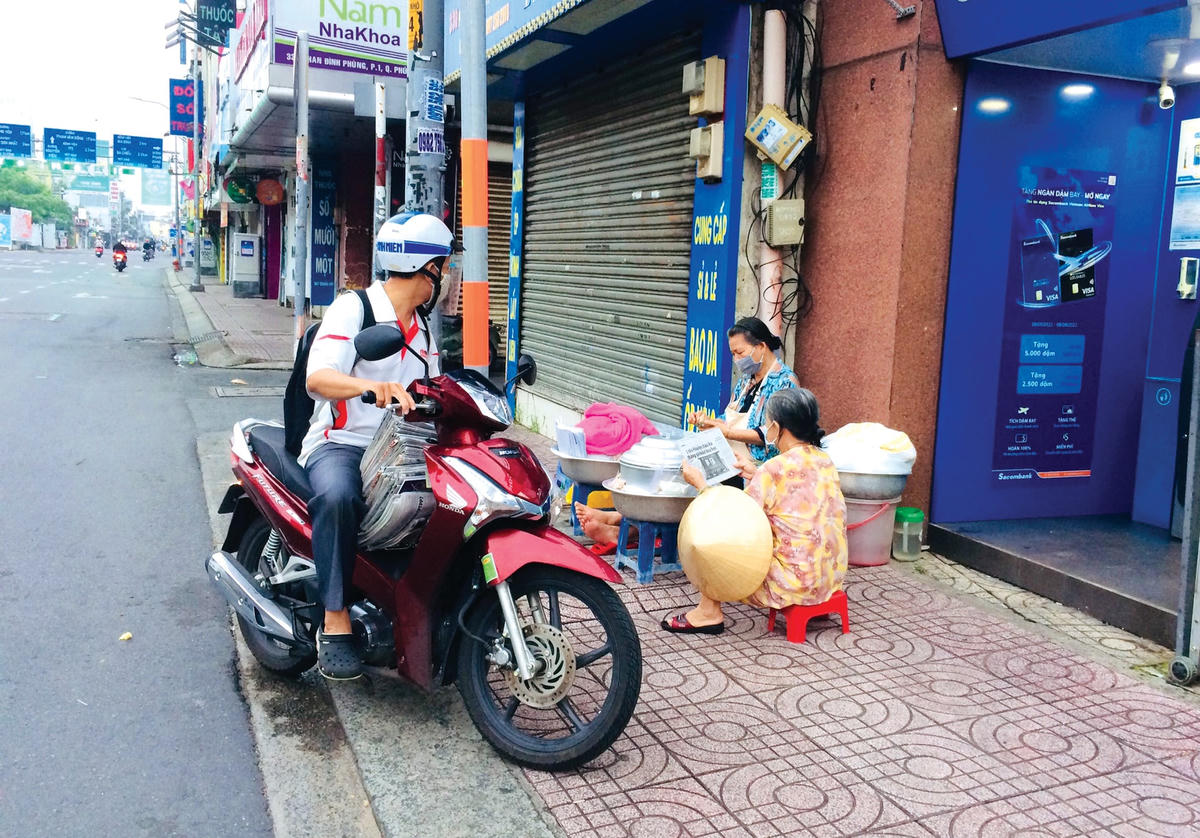 Nhân viên giao báo ghé mua xôi ven đường (hình chụp tại đường Phan Đình Phùng, quận Phú Nhuận).