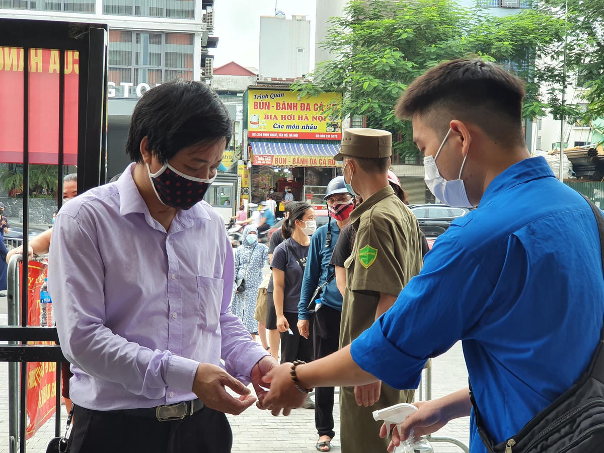 Đội ngũ thanh niên tình nguyện thực hiện việc sát khuẩn và đo thân nhiệt cho người dân.