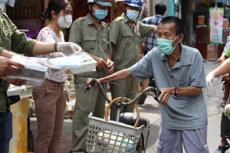 Khẩu trang, cơm chay được trao tận tay người nghèo tại 96 Nguyễn Chí Thanh, Quận 10. Ảnh: PLO.