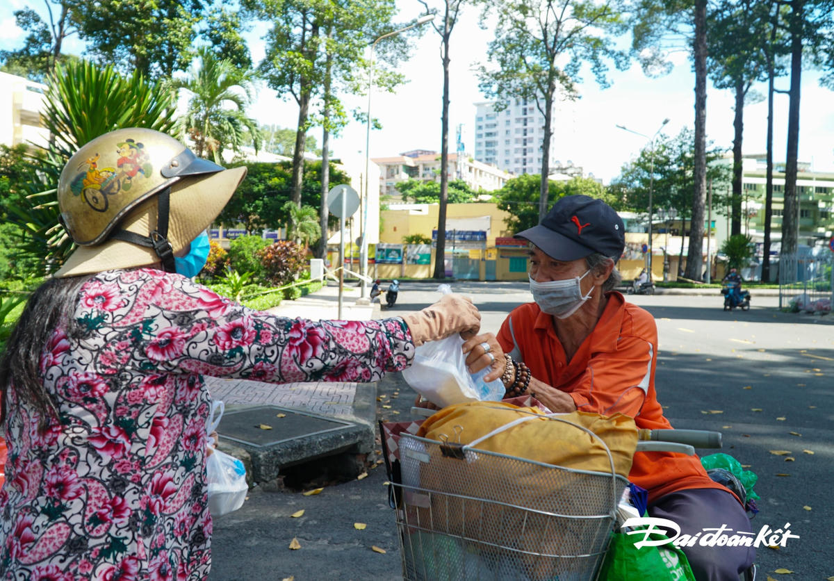 Tại một góc công viên, chị dừng là và gọi mọi người đến nhận cơm, để hạn chế tập trung đông, từng người đã lần lượt đến nhận.