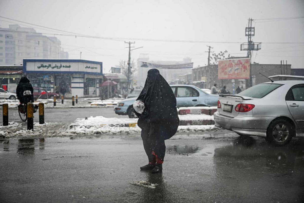 Một người phụ nữ mặc ‘burqa’ - trang phục truyền thống của người dân Afghanistan đi ăn xin trên đường khi tuyết đang rơi lạnh cắt. Ảnh: Mohd Rasfan / AFP / Getty.