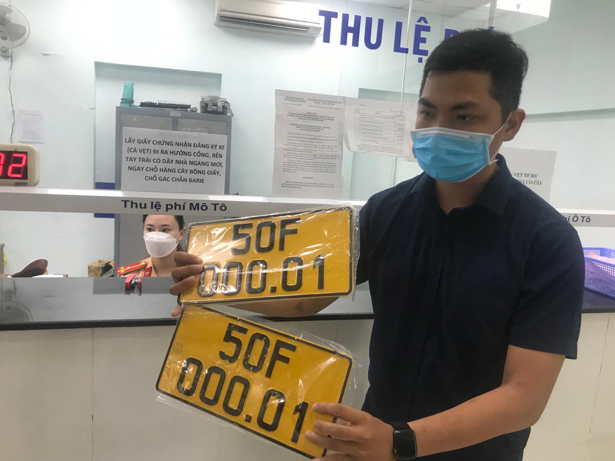 Một người dân vui mừng nhận biển số xe màu vàng.