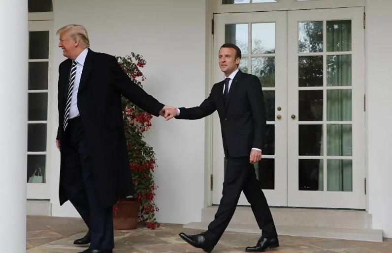 Tổng thống Pháp Emmanuel Macron và Tổng thống Mỹ Donald Trump tay trong tay đi dạo dưới hàng cột của Nhà Trắng ở Washington, DC, năm 2018.
