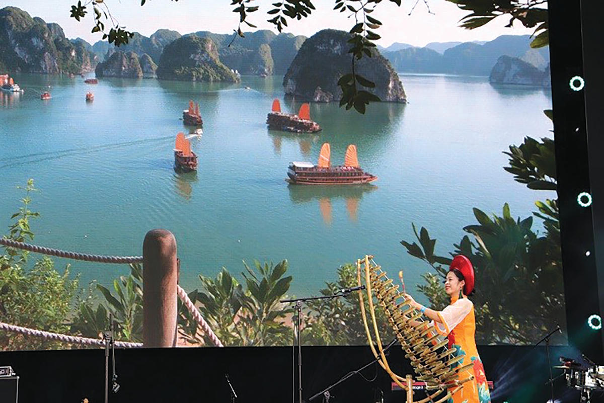 Nghệ sĩ Việt Nam trình diễn nhạc cụ dân tộc tại Tuần lễ “Di sản Thế giới Vịnh Hạ Long - Kỳ quan mới của thế giới” tại EXPO 2020 Dubai, với nền sân khấu phía sau là hình ảnh của Vịnh Hạ Long.