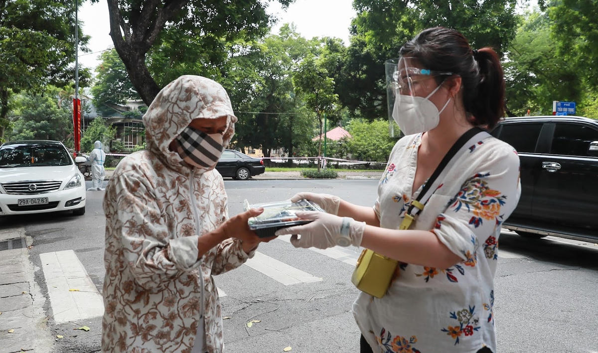 Cán bộ Báo Đại Đoàn Kết trao suất cơm cho người dân gặp khó khăn.