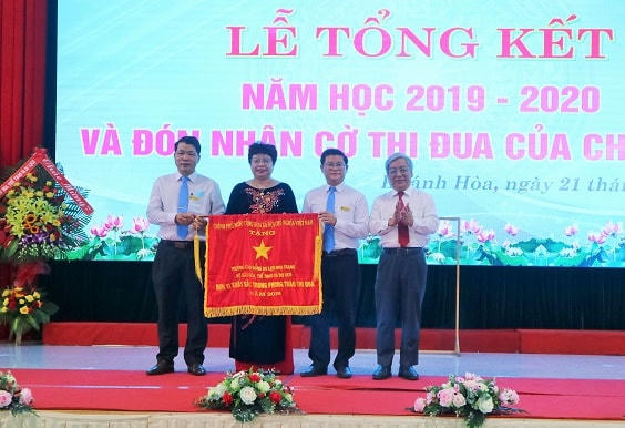 Ông Lê Xuân Thân, Trưởng đoàn đại biểu Quốc hội tỉnh Khánh Hòa trao Cờ thi đua của Chính phủ cho nhà trường.