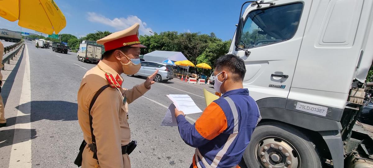 Phương tiện ra vào TP Hà Nội được kiểm tra giấy tờ tại chốt trên QL 1A. Ảnh: Nam Anh.