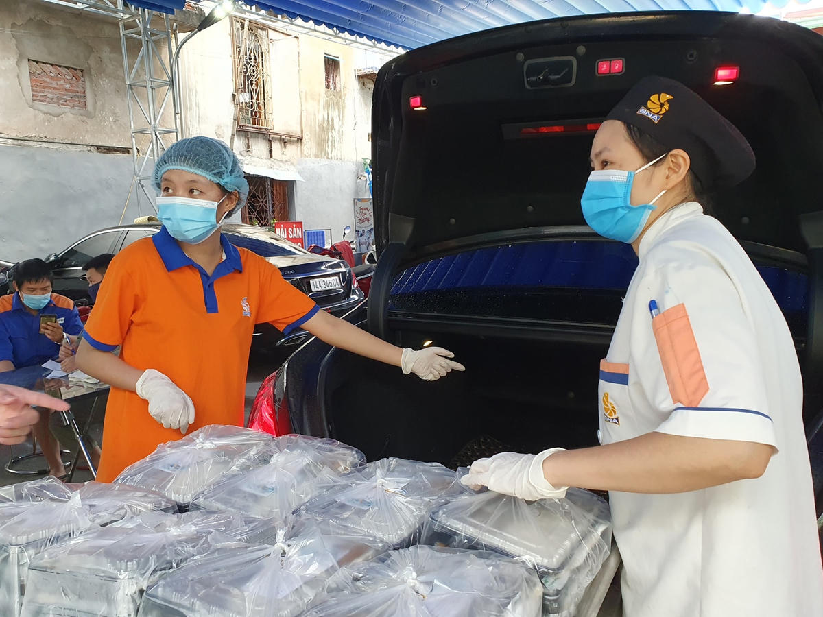 Đội ngũ tình nguyện viên cẩn thận xếp từng suất ăn lên xe để vận chuyển.