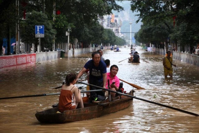 Người dân sử dụng thuyền để di chuyển trong một khu vực bị ngập lụt của thành phố Liễu Châu, Giang Tây, Trung Quốc hôm 11/7 (Ảnh: EPE-EPA).