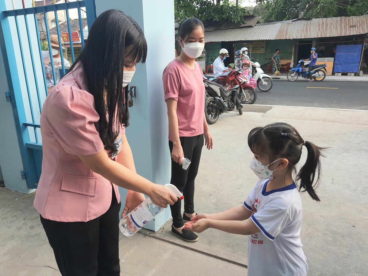 Đo thân nhiệt, rửa tay sát khuẩn cho trẻ mầm non trước khi vào lớp học trực tiếp.