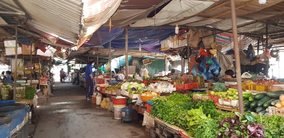 Cả một dãy sạp rau củ đầy ắp, tươi rói nhưng chỉ có một khách mua hàng tại chợ trung tâm Thị trấn Đông Anh.