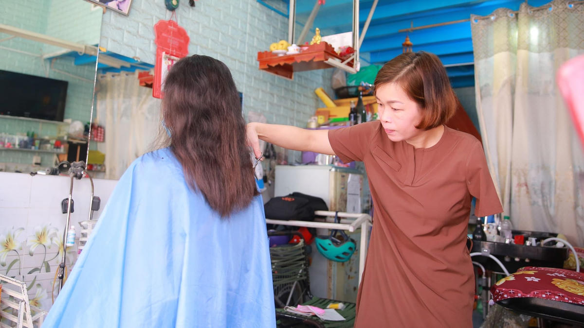 Chị Trâm cắt tóc bằng một tay.