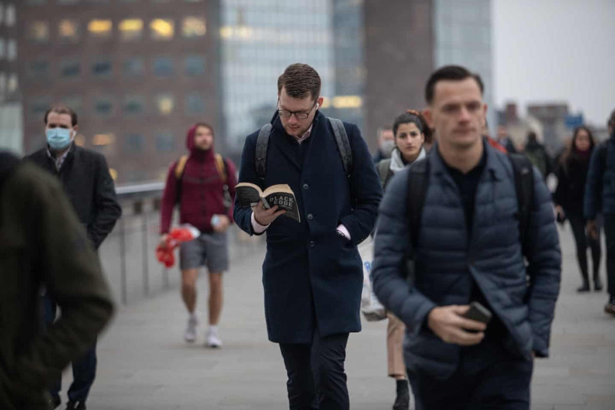 Người đàn ông tranh thủ đọc sách trên đường đi làm qua Cầu London. Ảnh: The Guardian.
