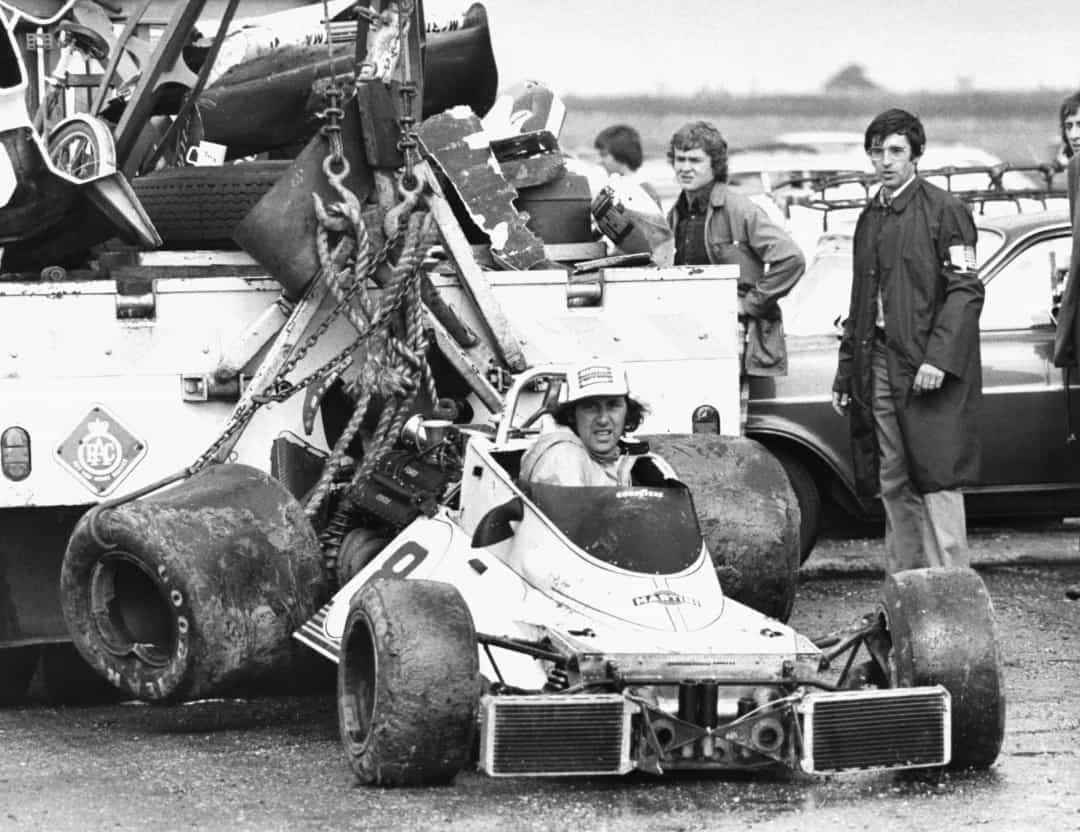 Tay đua Carlos Pace được nhìn thấy bị kéo đi trong chiếc xe bị đắm của mình sau một cuộc đổ bộ tại Grand Prix Anh 1975. Điều kiện thời tiết tồi tệ khiến hầu hết mọi tay đua đều có thể bị trượt bánh tại một số thời điểm, và cuộc đua đã bị dừng lại sớm sau 56 vòng đua.  