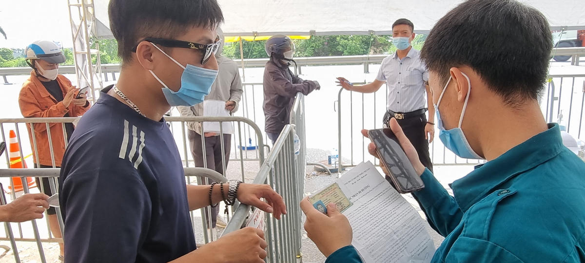 Thành viên chốt kiểm soát dịch bệnh Covid-19 hướng dẫn người dân khai báo y tế. Ảnh: Hà An.