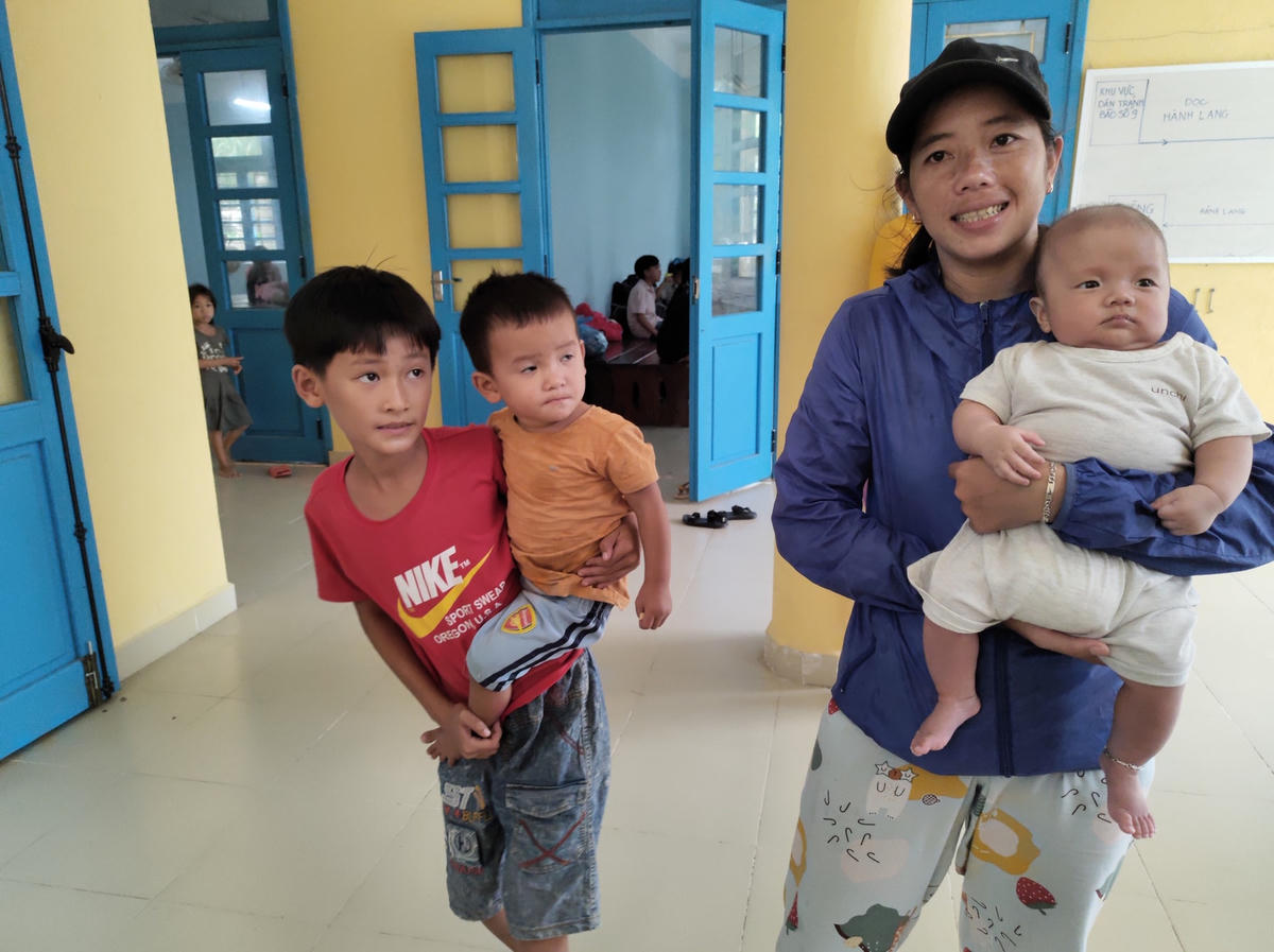 Chị Phan Thị Thu Lan (người bồng con) cho biết, đây là lần thứ 3 trong tháng nay chị phải cùng con mới sinh 3 tháng tuổi đi tránh bão lũ. Hai lần trước chị cùng con đến nhà bà ngoại ở khu vực cao ráo hơn để tránh lũ, tuy nhiên lần này theo dự báo bão lớn nên chị cùng con đến khu tránh bão tập trung để được an toàn. 