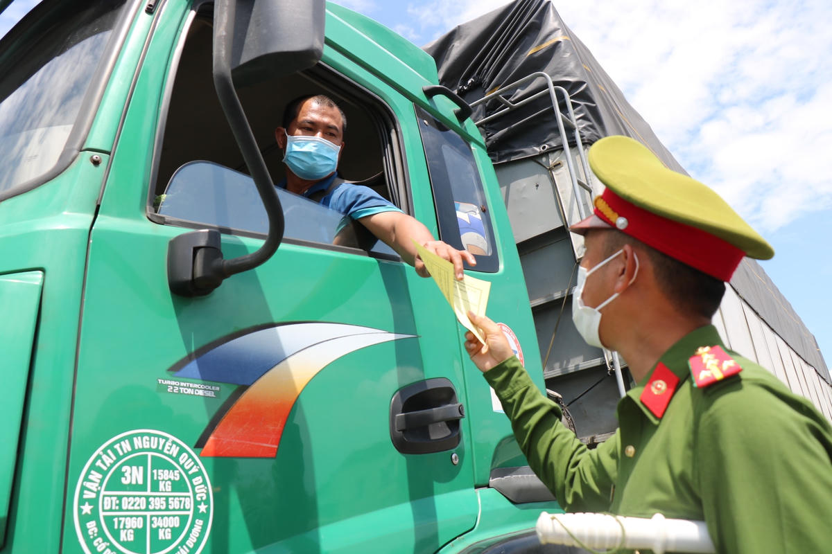 Một cán bộ Công an phát phù hiệu màu vàng (không dừng đỗ, đón trả khách/hàng hoá) cho những tài xế xe tải khi đi ngang qua địa bàn tỉnh Thừa Thiên - Huế.