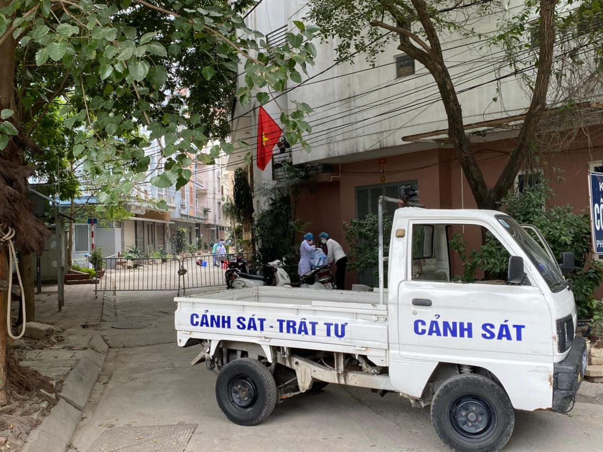 Lực lượng chức năng dựng hàng rào và chặn xe cánh sát từ cổng khu tập thể. Ảnh: Lan Anh.
