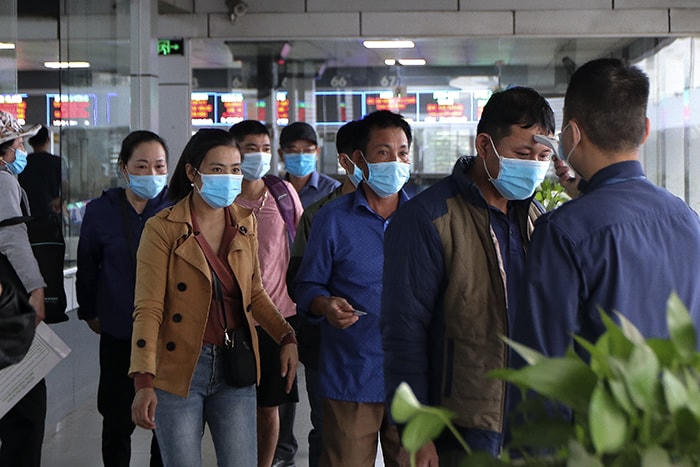 Đo thân nhiệt cho hành khách tại bến xe Nước Ngầm (Hà Nội).