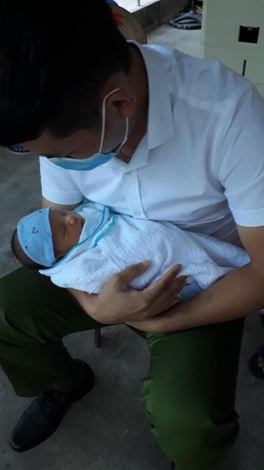 Cháu bé được một cán bộ công an xã bế ẵm sau khi được phát hiện bị bỏ rơi.