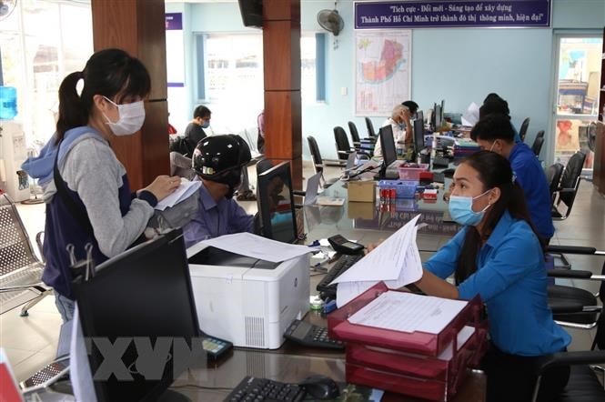 Cán bộ Ủy ban Nhân dân phường Hiệp Bình Chánh, thành phố Thủ Đức hướng dẫn thủ tục hành chính cho người dân. (Ảnh: Xuân Tình/TTXVN).