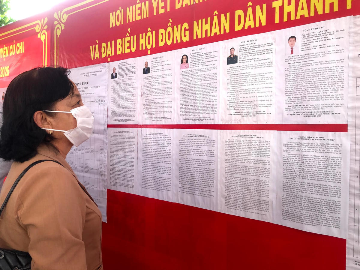 Người dân thị trấn Củ Chi đọc thông tin về các ứng viên trước khi chọn lựa để bầu cử.
