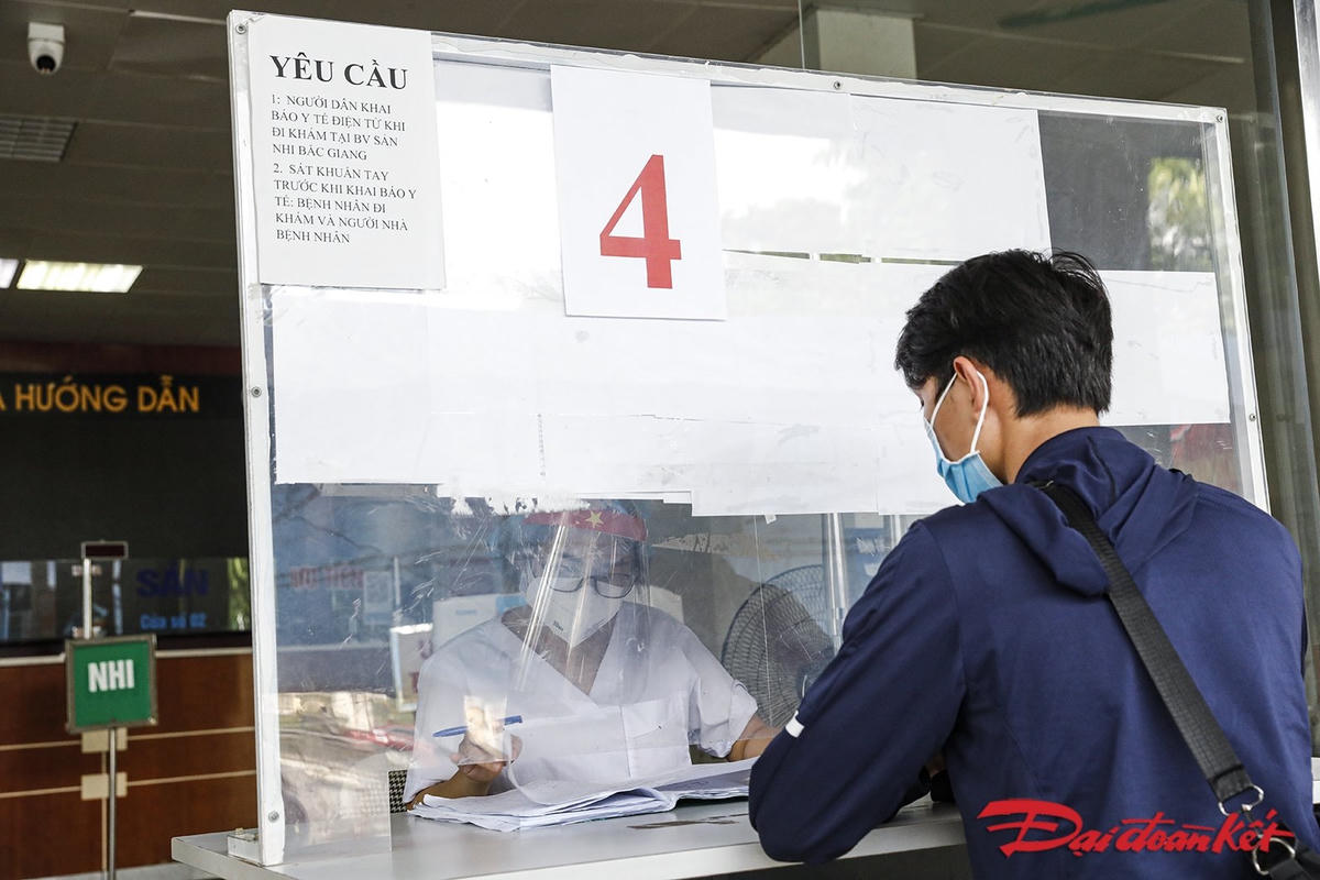 Sau khi được xét nghiệm Covid-19 nhanh, có kết quả âm tinh, người đến khám chữa bệnh vào khu vực tiếp theo, khai báo thủ tục để tiếp tục thực hiện quy trình khám. Ảnh: Quang Vinh. 