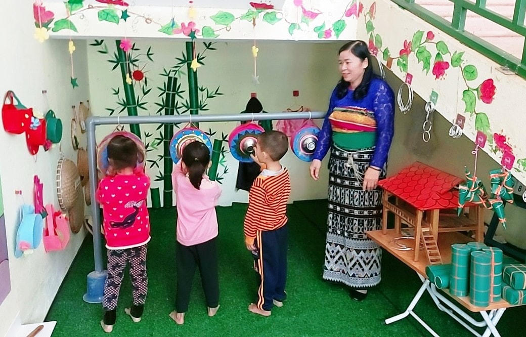 Cô Vi Thị Vinh hướng dẫn học sinh tập chơi đánh chiêng.