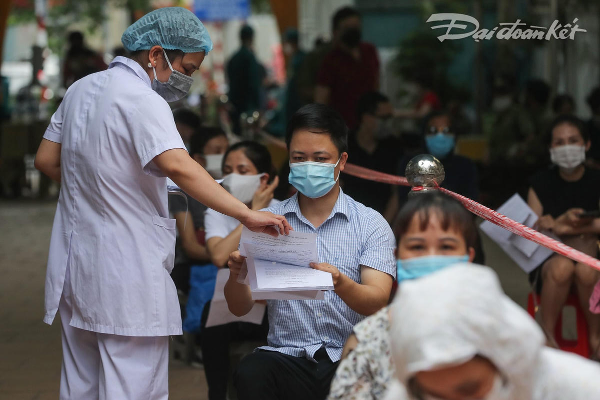 Cán bộ y tế phát phiếu sàng lọc cho từng người dân. Ảnh: Quang Vinh.