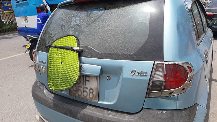Tinh vi hơn, có lái xe kẹp tấm che nắng vào cần gạt nước sau. Khi gặp CSGT chỉ cần bật công tắc là tấm che nắng rơi khỏi xe.