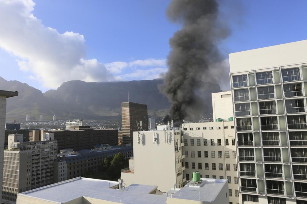 Một đám khói lớn bốc lên phía trên Tòa nhà Quốc hội, phía sau Nhà thờ St. George, ở Cape Town, Nam Phi. Ảnh: AP.