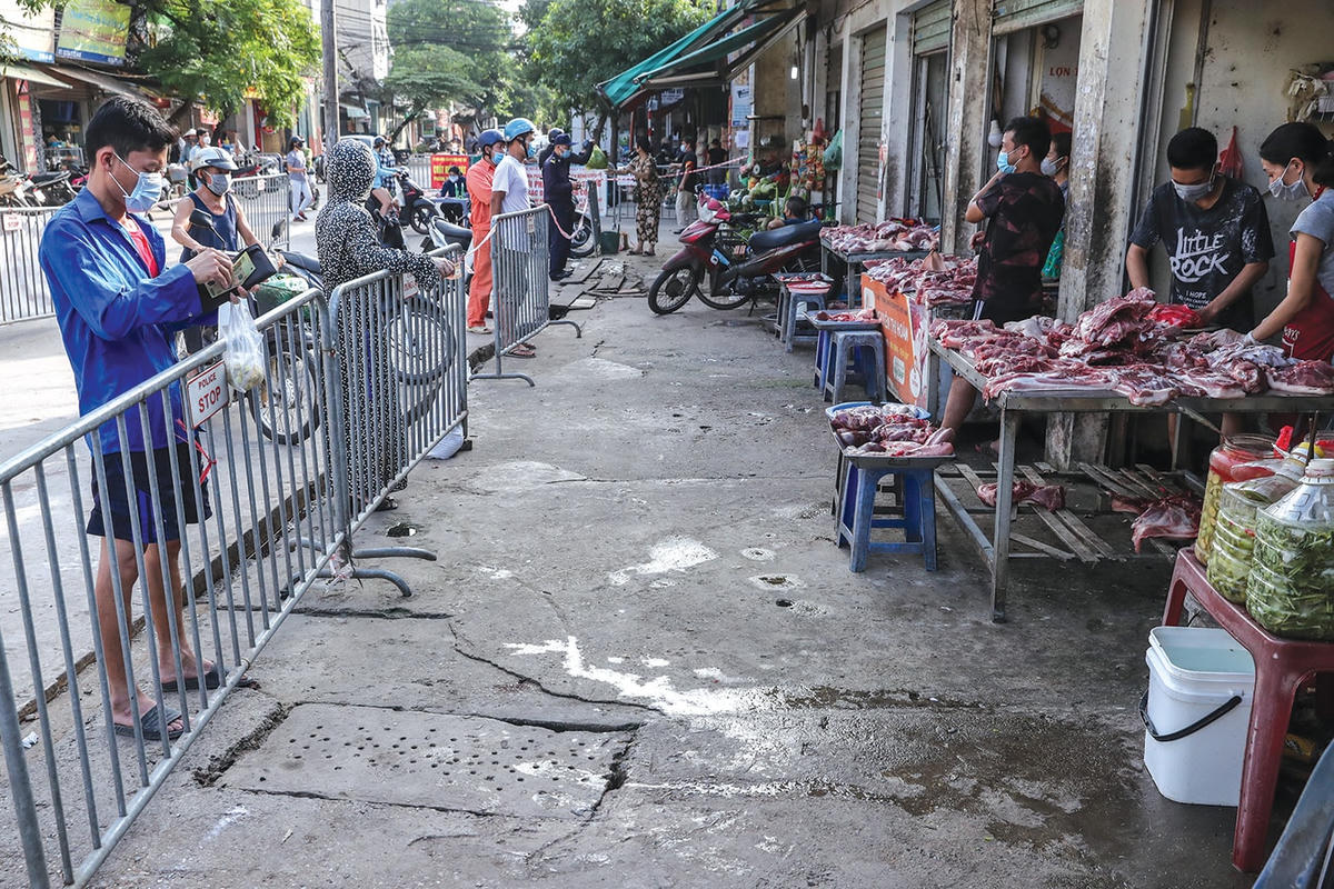 Người dân mua hàng ở phía ngoài cổng chợ phải xếp hàng và giữ khoảng cách tại các kiốt.