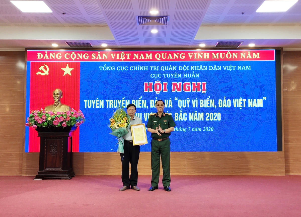 Thượng tướng Trần Quang Phương tặng hoa chúc mừng họa sĩ Trịnh Bá Quát với biểu trưng đạt giải nhất Cuộc thi sáng tác Logo “Quỹ vì biển, đảo Việt Nam”. Ảnh: Trung Quân.