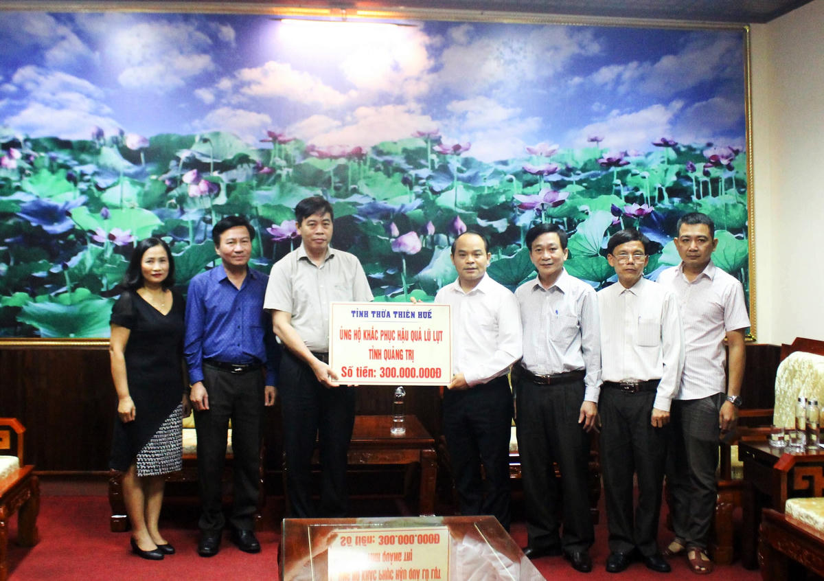 Lãnh đạo tỉnh Thừa Thiên - Huế (phải) trao 300 triệu đồng hỗ trợ người dân trên địa bàn tỉnh Quảng Trị khắc phục hậu quả mưa lũ.