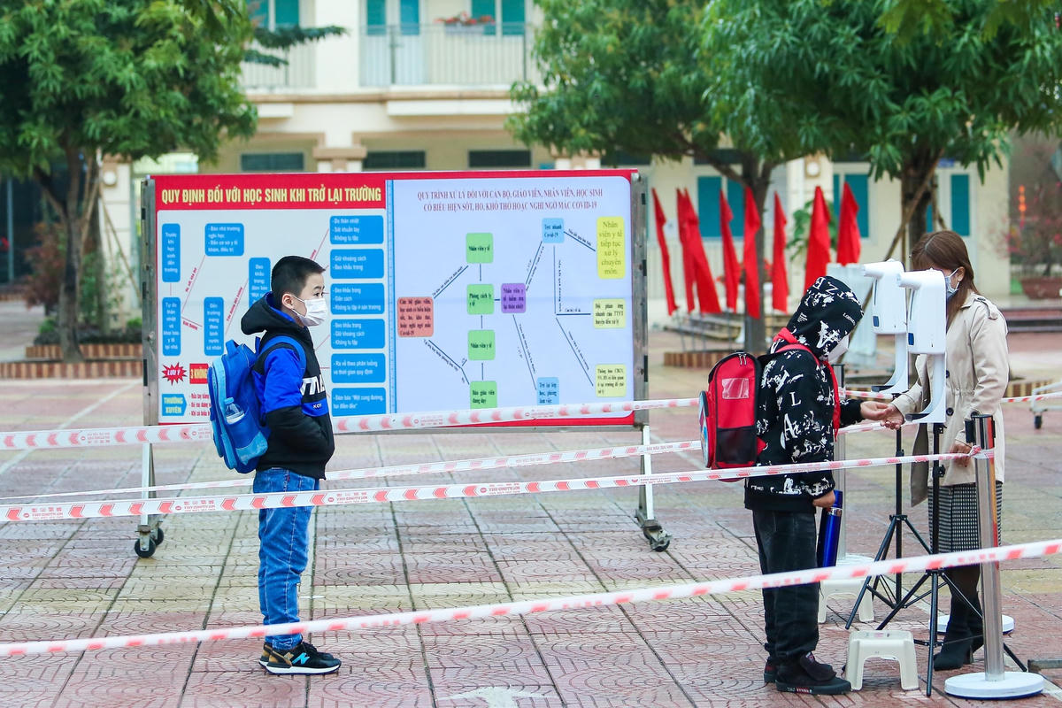 Học sinh đo thân nhiệt trước khi vào lớp học trực tiếp.