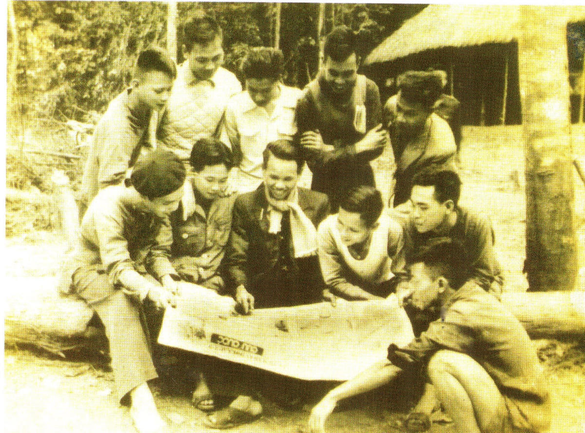 Xem Báo Cứu Quốc mới in xong ở đèo Bụt (Bắc Giang - 1948). Người ngồi giữa, quàng khăn là Chủ nhiệm Xuân Thủy.