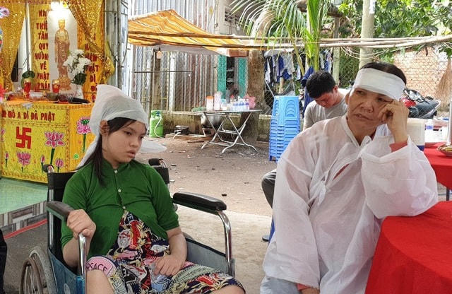Bà Nguyễn Thị Bích Thủy (vợ ông Tài) ngồi bên cô con gái 14 tuổi bị bệnh bại não, đau buồn kể về cuộc đời vất vả của gia đình.