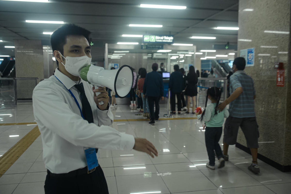 Nhân viên nhà ga liên tục phải sử dụng loa để nhắc nhở hành khách đứng giãn cách.